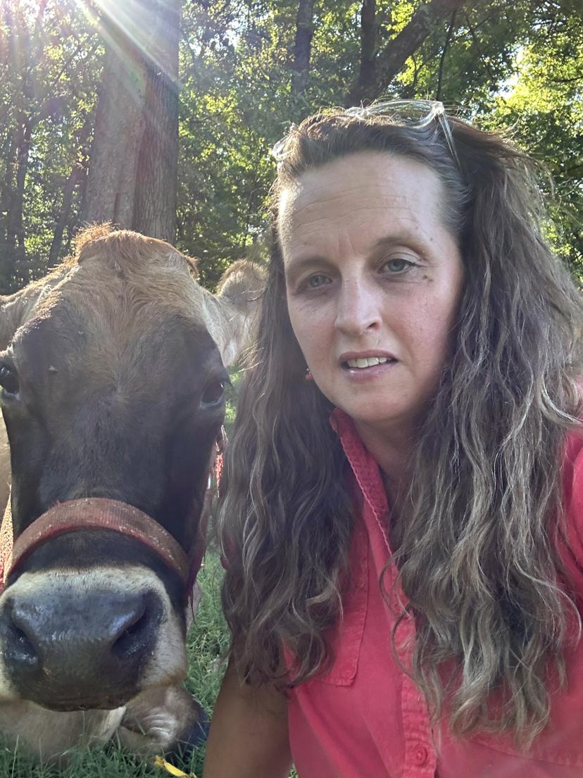 A farmer and a Jersey cow sharing a sunny moment together